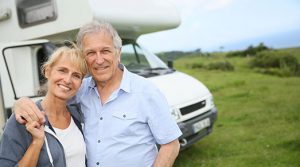happy retired couple outside their RV camper